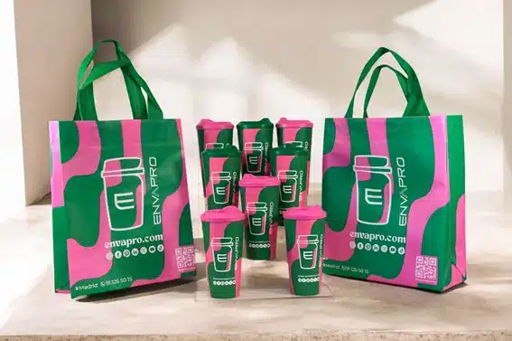 Bolsas reutilizables y vasos con tapa personalizados en verde y rosa con la imagen de Envapro