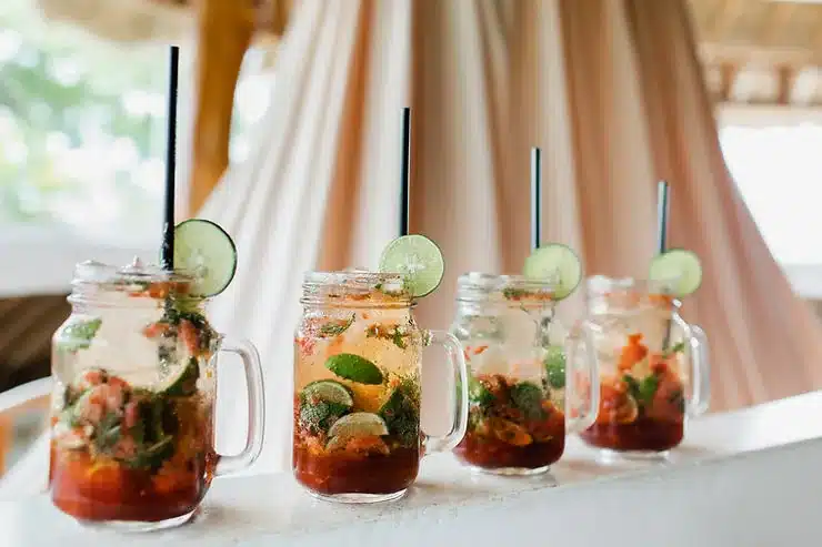 Cuatro cócteles de frutos rojos y lima en tarros de cristal con asa y pajitas negras