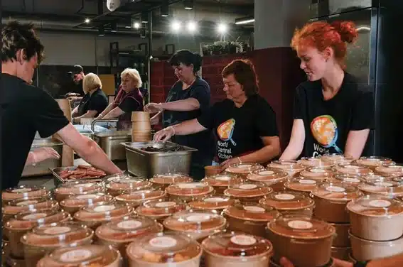 Voluntarias de World Central Kitchen preparando comidas en envases de cart&oacute;n con tapa