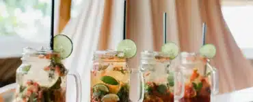 Cócteles en tarros de cristal con lima, hierbabuena y pajitas negras sobre una barra