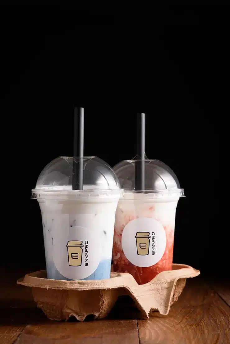 Dos vasos de bubble tea con tapa c&uacute;pula y pajita negra, personalizados con el logo de Envapro, en un portavasos de cart&oacute;n